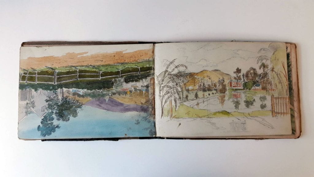 Page 53 (Left): Landscape watercolour (upside down). The view looks over dirt road, to a white fence, then a paddock, a line of bushes, a house to right, then the rest of town towards the foothills. Blue sky. Richmond church spire is visible. Page 54 (Right): Landscape pencil and watercolour sketch. A body of water before a red house, another smaller house or building with a blue roof, and golden hills behind. Red house and trees are reflected in water. 