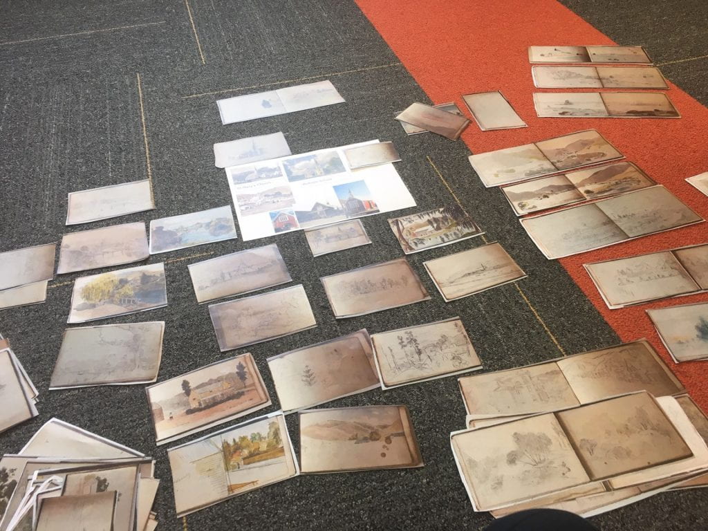 Photo of an office floor chaotically covered with little sketches roughly the size of your hand