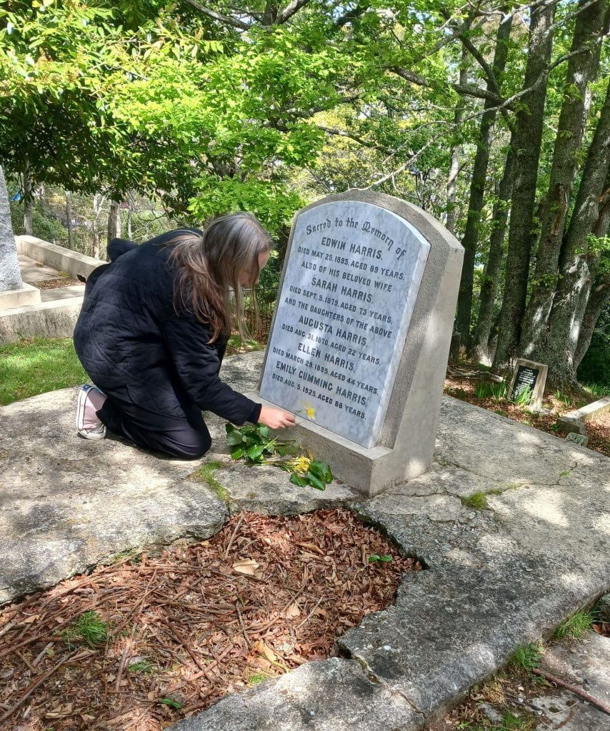 Catherine placing kawakawa leaves on the Harris family grave