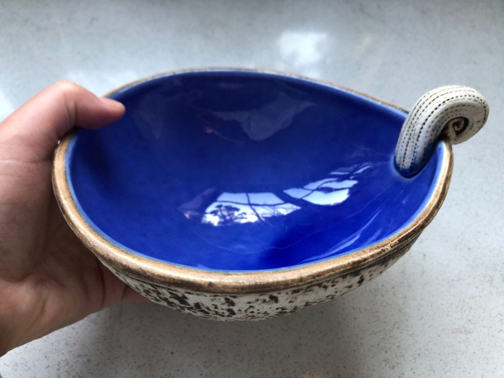Ceramic bowl, glazed blue on the inside, with a koru handle