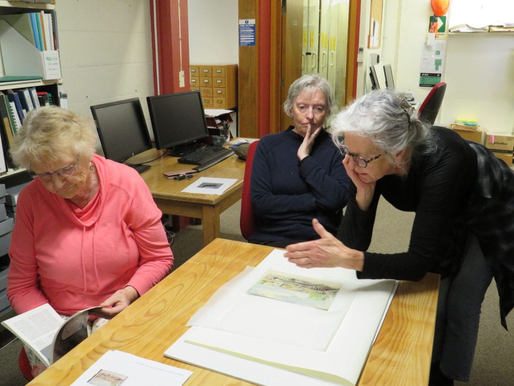 Mary Gavin, Michele Leggott and Susan Davis talking about a painting in the Isel Park Rsearch Centre